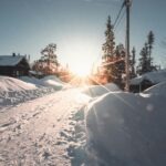 Serene winter sunrise illuminating a snowy path and trees in Sweden with dramatic sunrays.